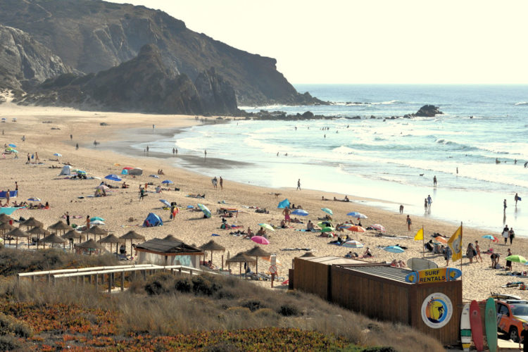 An mass gathering of surfers at one of the world's great surf beaches. Dramatic dark cliffs and big waves are guaranteed